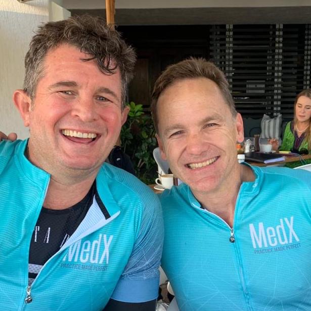 Two smiling riders in MedX cycling jerseys